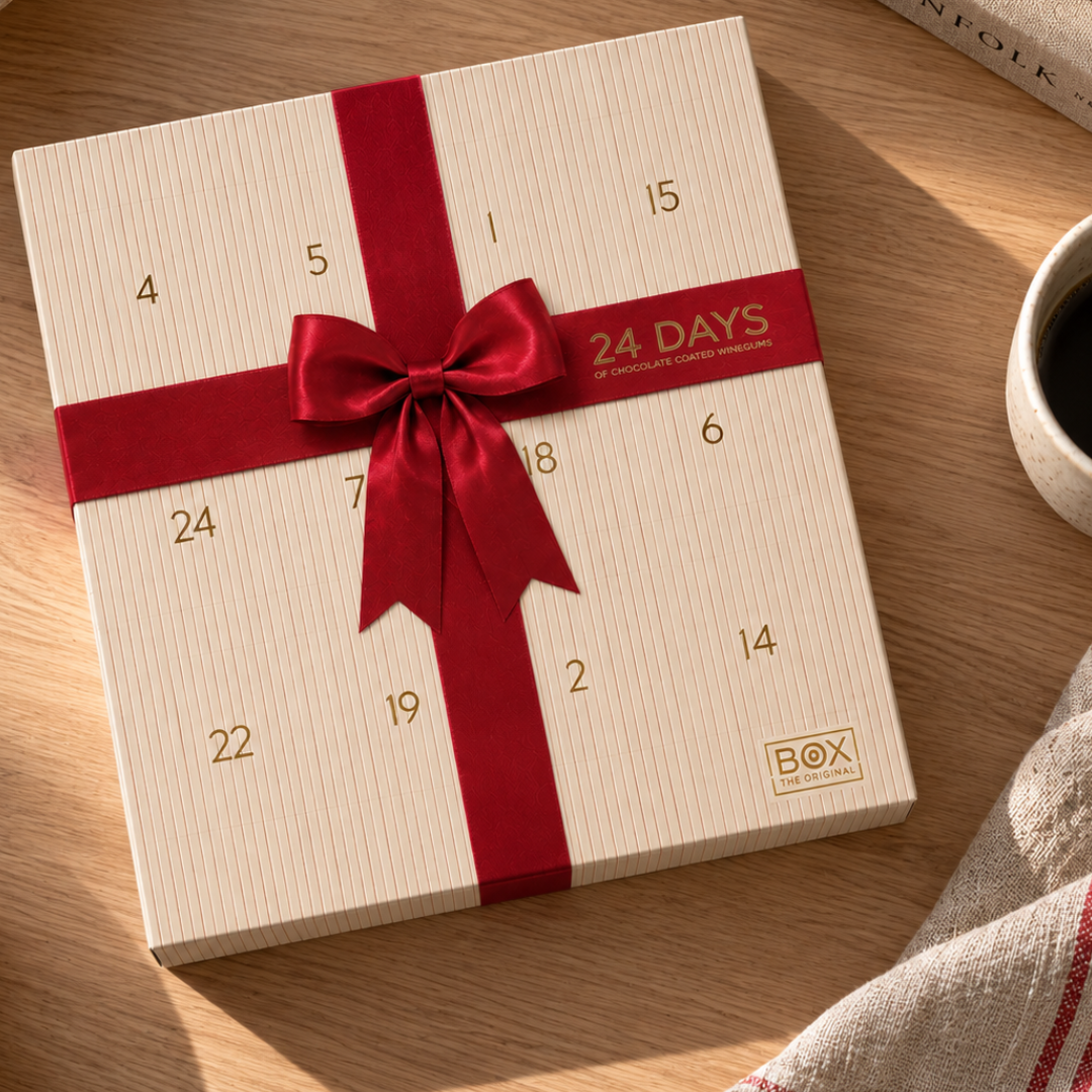 Cremefarvet julekalender med rød sløjfe og guldfarvede tal 1-24 fra Box The Original