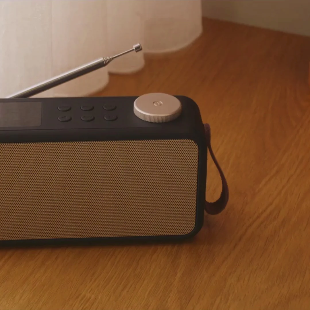 Sort DAB+ radio med beige stofgitter, sølv antenne, drejeknap og bærerem