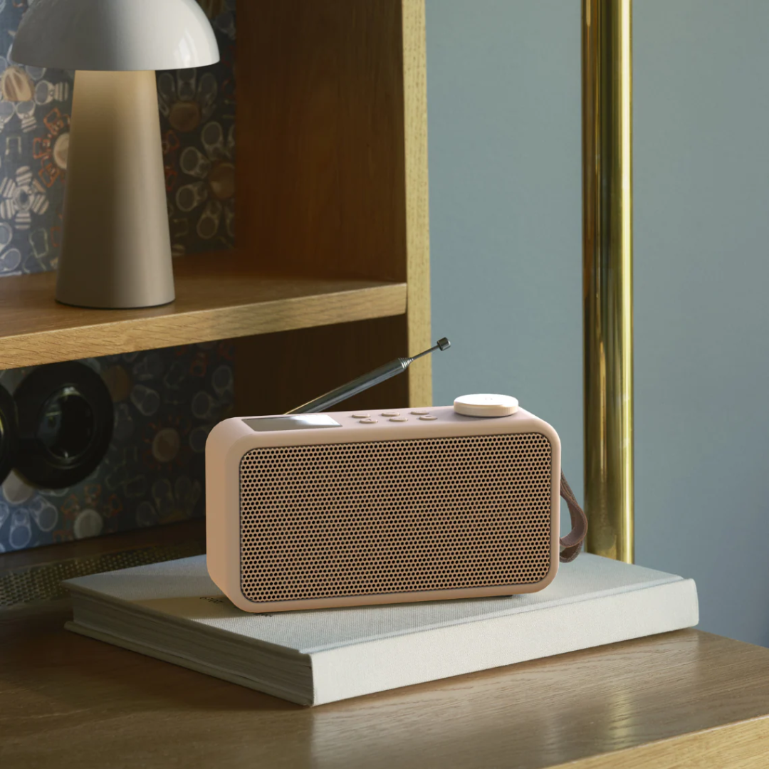 Lyserød DAB+ radio med metalnet-gitter, antenne og rund volumenknap i retrodesign