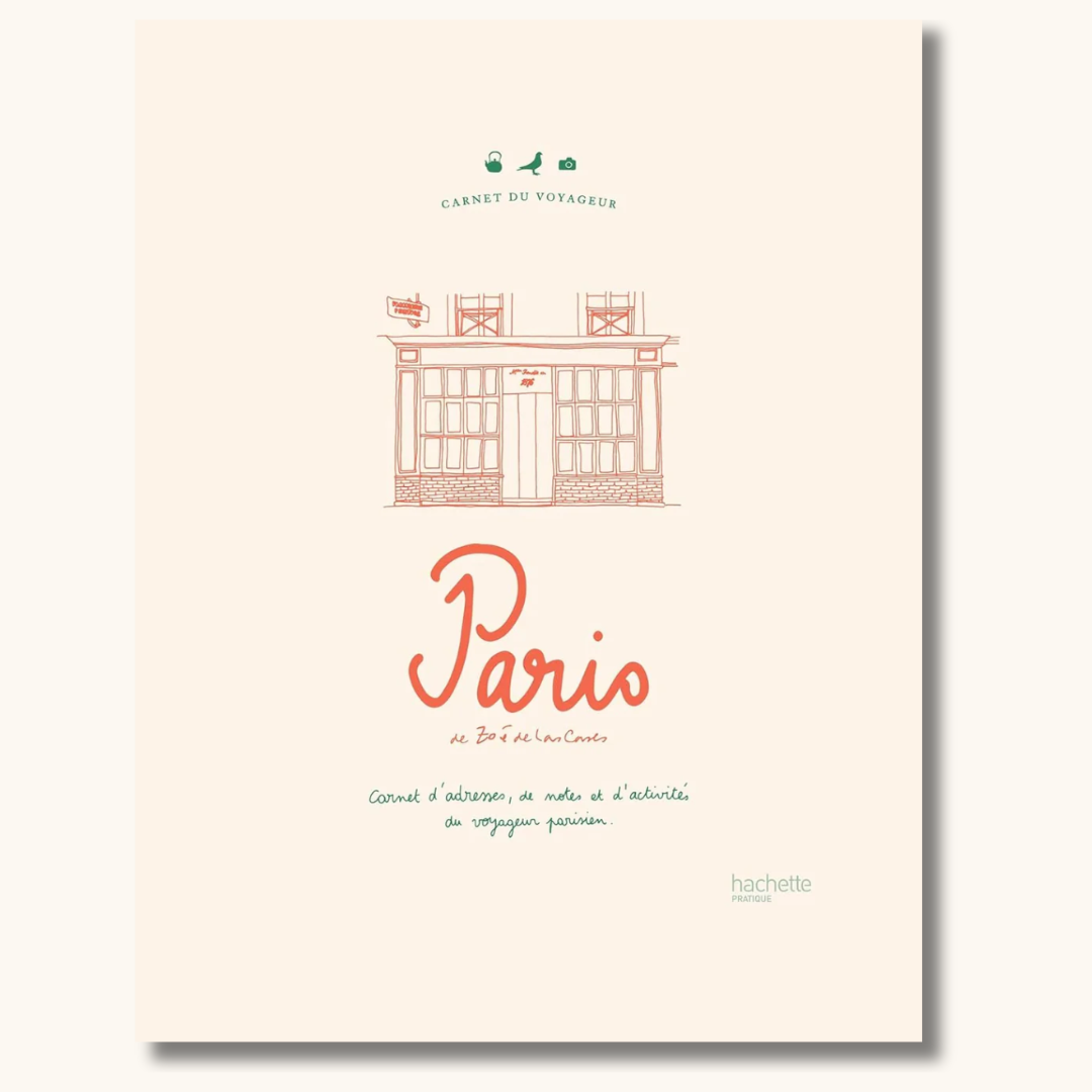 Beige hardcover rejsedagbog om Paris med rød håndskrift og illustration af parisisk facade