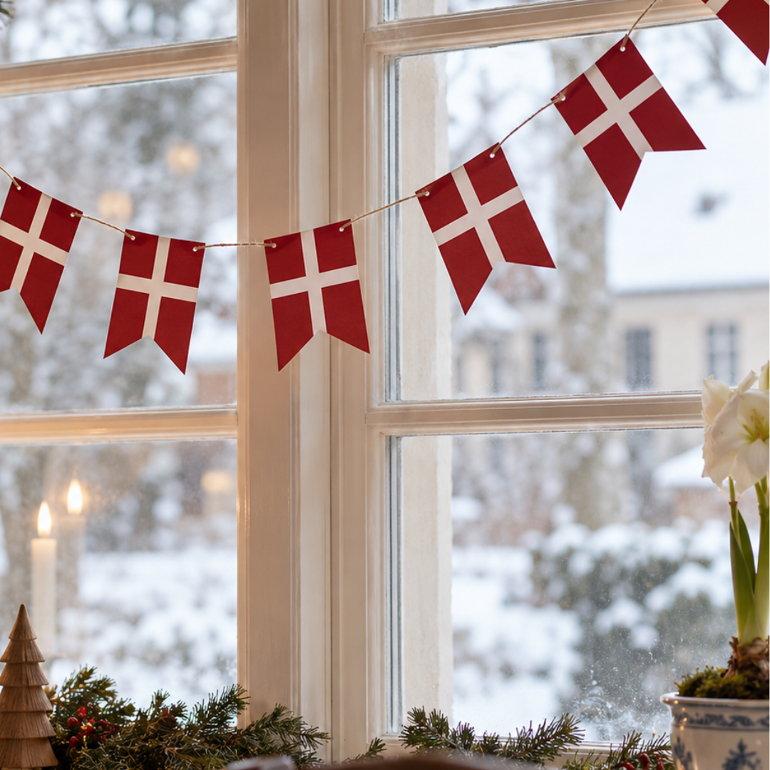 Rød og hvid Dannebrog flagguirlande i papir hængt op foran et vindue