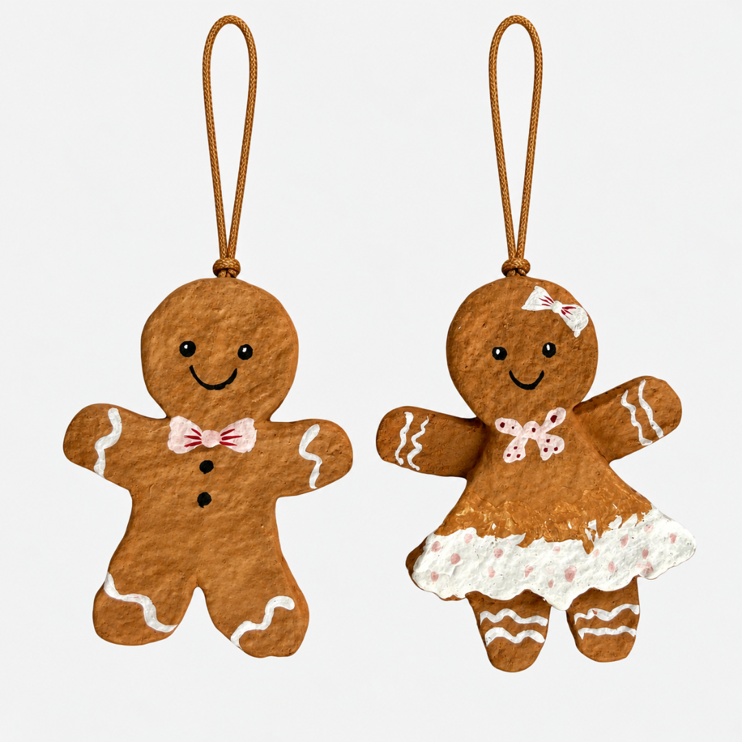 To brune papmaché honningkagefigurer med hvide detaljer og snor til ophæng