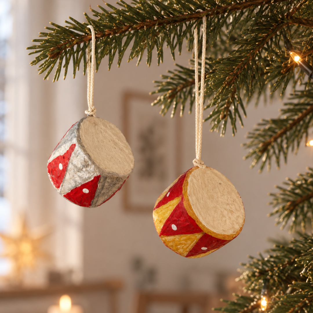 To håndmalede papmaché-tromme-juleophæng i rød/sølv og rød/guld hængt i juletræ