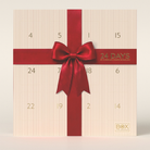 Cremefarvet julekalender med rød sløjfe og guldfarvede tal 1-24 fra Box The Original