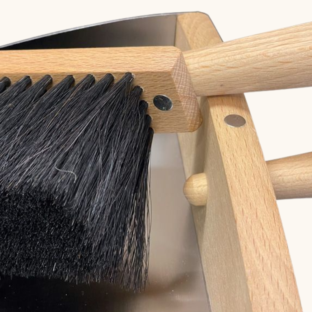 Nærbillede af fejekost med sorte hestehår og håndtag i naturligt bøgetræ med magneter