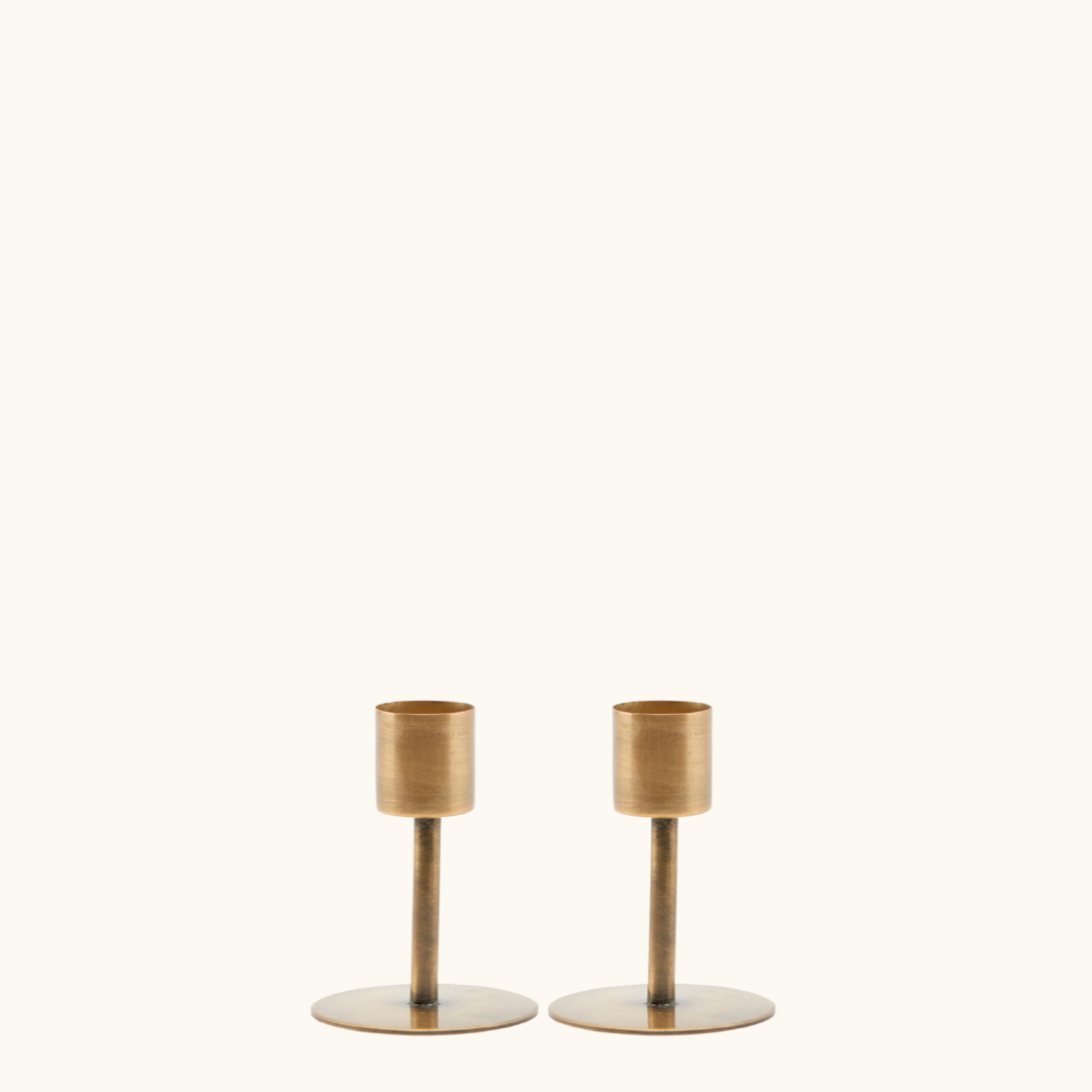 2 lysestager i jern med antik messingfinish, rund flad fod og smal stang med cylindrisk lysholder øverst