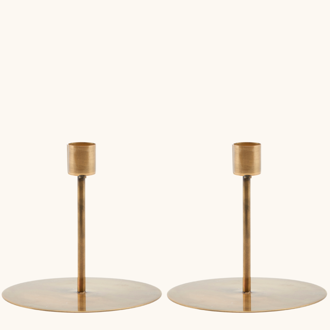 To lysestager i jern med antik messingfinish, rund flad fod og smal stang med cylindrisk lysholder øverst