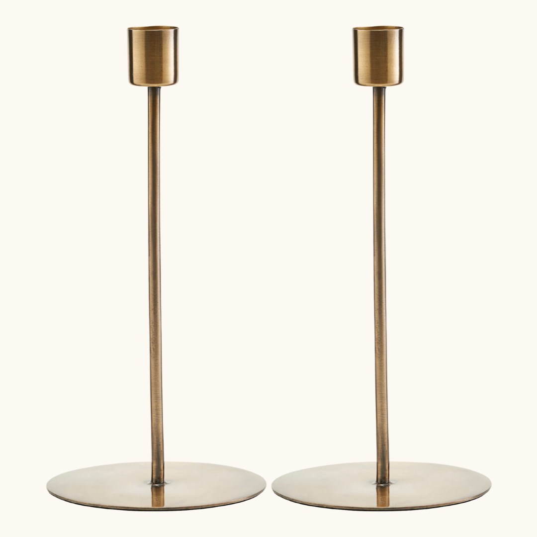 2 lysestager i jern med antik messingfinish, rund flad fod og smal stang med cylindrisk lysholder øverst