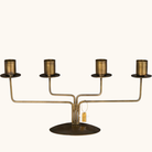 4-armet lysestage i antik messing-farvet metal med oval fod og fire cylindriske lyseholdere