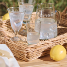 Håndflettet rattanbakke i natur med glas og kande til servering