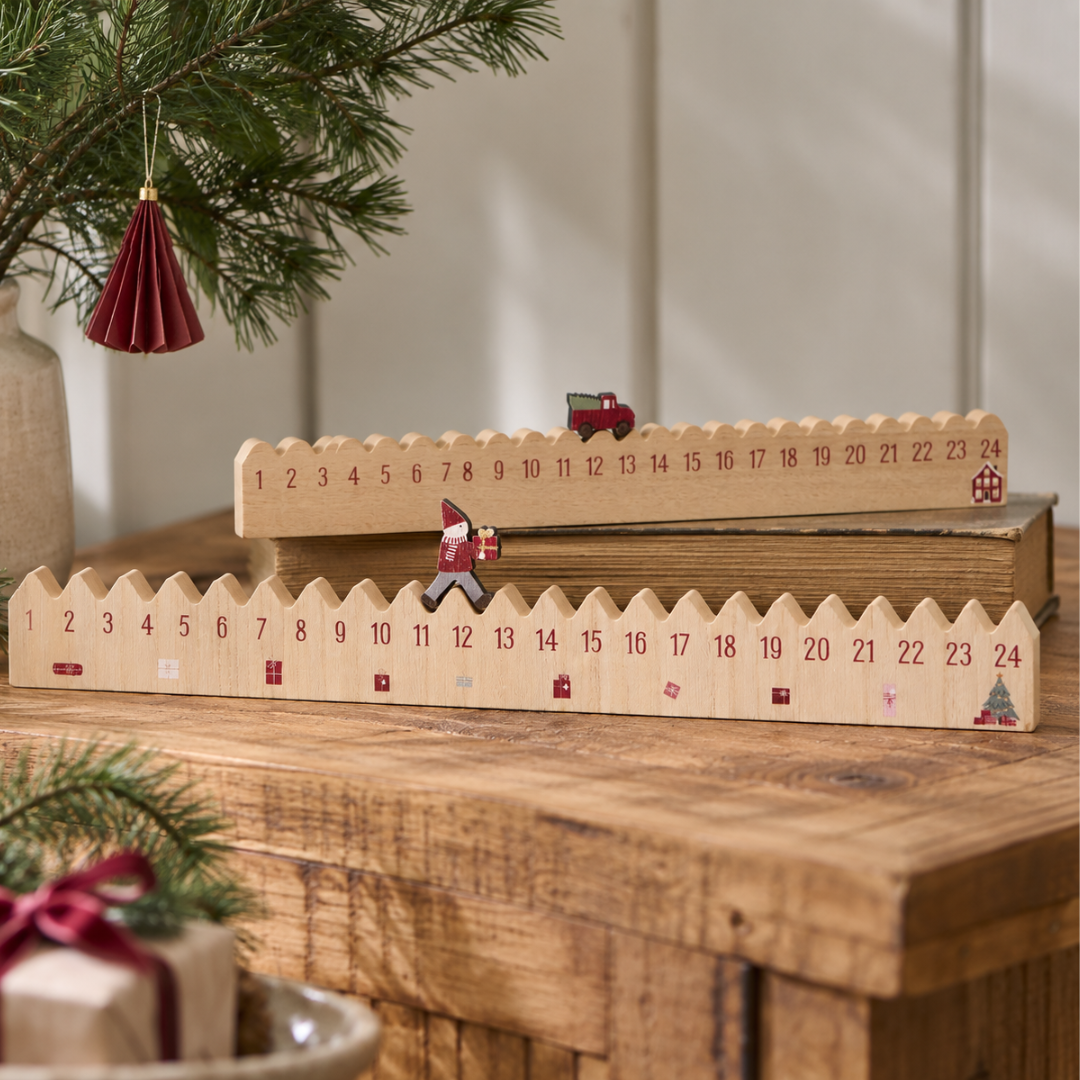 To naturfarvet MDF julekalendere med tal 1-24 og røde julemotiver, en med nisse og en med ladbil