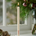 Tyndt cremefarvet kertelys med rød God Jul-tekst og hjerte, tændt med flamme