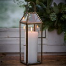 Lanterne Laurits i antik messing med klart glas og hvidt bloklys med tændt flamme