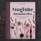 Magiske blomsterfrø af Rikke Lentz, indbundet bog med lyserødt omslag og tørrede blomster