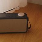 Sort DAB+ radio med beige stofgitter, sølv antenne, drejeknap og bærerem