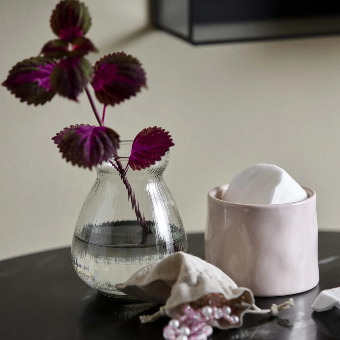 Rund, buget vase i klart riflet glas med lilla blomstergrene