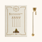 Guldfarvet metal balance lysholder med spiraltopp og kugle i bunden, vist med æske