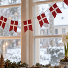 Rød og hvid Dannebrog flagguirlande i papir hængt op foran et vindue