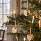 Tre små papirjuletrommer i rød, hvid og guld hængt på juletræ med snor