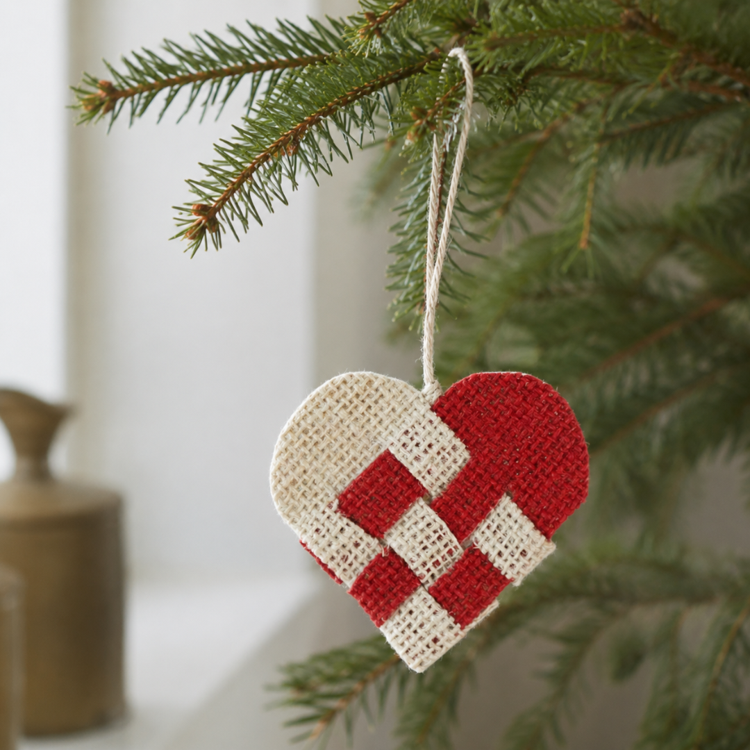 Flettet julehjerte i rød og creme jute med snor, hængt på juletræsgren
