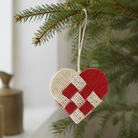 Flettet julehjerte i rød og creme jute med snor, hængt på juletræsgren