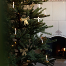 Sløjfeformet juleophæng i antik messing hængt på grønt juletræ