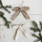 To hæklede julesløjfer i jute, én brun og én offwhite, med ophængsnor