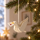 Cremehvid papmaché-due med gult næb og hvidt brev med rødt hjerte, hængt i juletræ